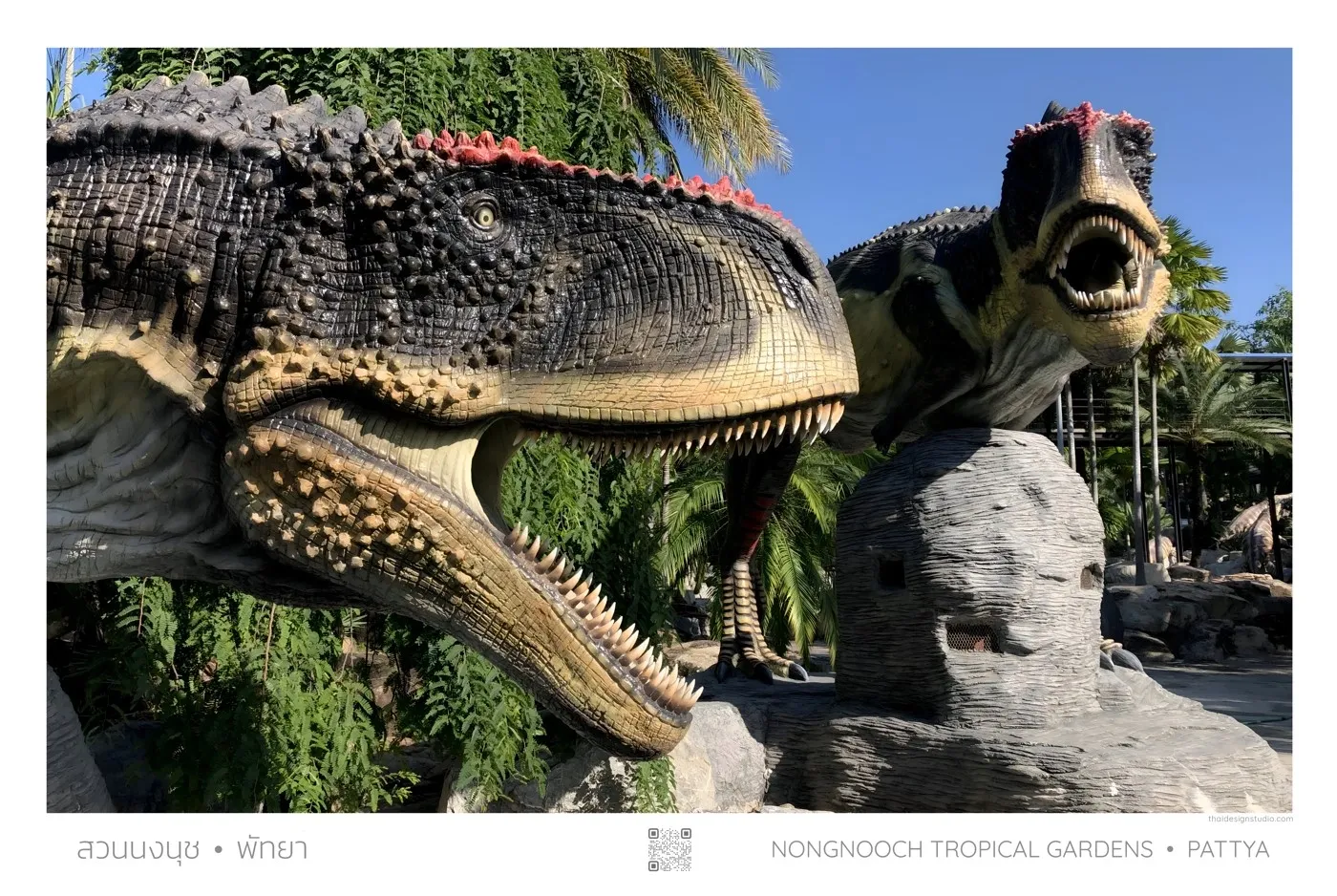 Two dinosaur statues in tropical garden.